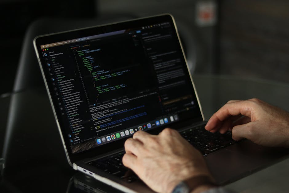 A close-up photograph of a computer screen displaying lines of multicoloured code in red, green, blue, purple, and yellow characters against a dark background. The text appears to be HTML or programmi